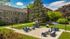 Charming courtyard view with stylish outdoor seating, lush green lawns, and historic stone architecture under a bright blue sky.