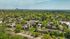 Aerial view of charming suburban neighborhood with lush green trees, red-brick buildings, and distant city skyline.
