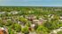 Scenic aerial view of a lush, tree-filled residential community with charming brick buildings and winding roads.