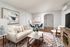 Elegant living room featuring a plush cream sofa, chic marble coffee table, abstract wall art, and warm hardwood floors, exuding modern comfort and style.