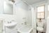 Bright, contemporary bathroom with sleek white tiles, modern vanity, and inviting bathtub.