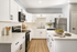 Modern kitchen with elegant white cabinetry, stainless steel appliances, and a sleek countertop adorned with fresh green apples.