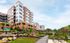 Contemporary apartment complex surrounded by lush landscaping and a scenic walking path, offering modern living in a tranquil setting.
