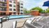 Luxurious outdoor pool area with stylish lounge chairs and vibrant blue umbrellas at a modern apartment complex.