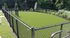 Inviting outdoor recreational space with lush artificial turf, enclosed by a sleek black chain-link fence, ideal for relaxation and sports activities.