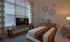Cozy bedroom with a vibrant striped bedspread, modern decor, and ample natural light through large window blinds.