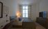 Elegant bedroom with soft lighting, featuring modern decor, a cozy bed, and a large window with patterned curtains.