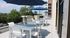 Inviting rooftop terrace featuring chic white outdoor furniture and vibrant blue umbrellas, complemented by lush green views.
