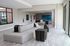 Modern communal lounge featuring elegant gray seating, natural light from large windows, and chic decor with contemporary artwork.
