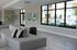Modern apartment lobby with stylish gray seating, vibrant artwork, and large windows offering a poolside view.