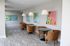 Bright and modern lounge area featuring stylish round tables, plush brown chairs, and vibrant wall art under elegant pendant lighting.