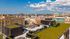 Breathtaking cityscape view from a modern rooftop terrace, featuring lush green spaces and stylish seating areas against a vibrant urban backdrop.