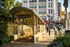 Bright city scene featuring Broad-Spring Garden subway entrance, surrounded by lush greenery and bustling urban life.