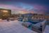 Luxurious rooftop terrace featuring stylish seating with panoramic cityscape views at sunset.