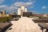 Luxurious rooftop terrace offering stylish seating and stunning cityscape views under a vibrant blue sky.