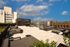Chic urban rooftop terrace with stylish furniture offering a panoramic city view under a bright blue sky.