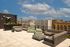 Chic rooftop terrace with stylish lounge furniture offering stunning city views under a bright blue sky.