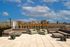 Chic rooftop terrace with stylish seating and stunning cityscape views under a clear blue sky.
