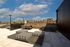 Stunning rooftop terrace with modern seating and cityscape views, perfect for relaxing and entertaining under a clear blue sky.