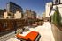 Stunning urban rooftop patio featuring modern lounge chairs, vibrant seating, and panoramic city views on a sunny day.