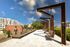 Inviting outdoor space with artistic benches, modern architecture, and urban views under a bright blue sky.