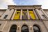 Grand facade of a historic city building adorned with vibrant banners from a college promoting inspiration and growth.