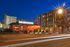 Vibrant urban scene with a modern apartment building and a stylish, well-lit restaurant at dusk.