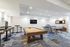 Vibrant recreation room featuring a modern pool table, ping pong table, and stylish bar seating, perfect for entertainment and relaxation.