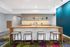 Contemporary kitchen layout with a stylish wooden countertop, elegant stools, and vibrant decor creating a welcoming atmosphere.