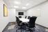 Modern conference room with sleek black chairs, a long white table, and vibrant carpeting.
