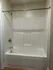 Modern and sleek white bathtub with a chrome shower fixture, providing a clean and inviting space for relaxation.