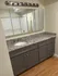 Elegant bathroom featuring a granite countertop with dual sinks, sleek grey cabinetry, and a large mirror with modern lighting.
