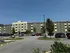 Contemporary apartment building with vibrant green and yellow facade, ample parking, and lush greenery, offering an inviting living experience.