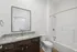 Elegant bathroom with a granite countertop, modern sink, and sleek shower-tub combo.