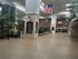 Spacious and bright atrium with high ceilings, lush indoor greenery, and prominent national flags creating an inviting atmosphere.