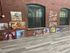 Charming brick loft featuring large windows and a display of vibrant art pieces enhancing the elegant wooden flooring.