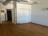 Bright apartment room with wooden floors, white walls, and modern exposed ducting; featuring a closet and open door leading to a spacious layout.
