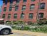 Charming red brick building with elegant arched windows and lush garden, perfect for stylish living.