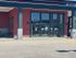 Elegant entrance of a modern building with large glass doors and red brick facade at Palm Square.