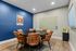 Modern meeting room with a sleek black round table and stylish leather chairs, complemented by vibrant blue accent wall, wooden flooring equipped with dry erase boards.