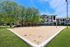 Inviting outdoor sand volleyball court surrounded by lush greenery and modern apartments, perfect for social gatherings and fitness enthusiasts.