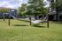 Inviting outdoor space with cozy hammocks under lush trees, perfect for relaxation at modern apartment complex.