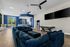 Chic open-concept clubhouse with wet bar with plush blue sofas, stylish kitchen, and abundant natural light, perfect for entertaining.