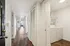 Contemporary apartment hallway with rich wood flooring, bright white walls, and a convenient in-unit laundry area.