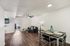 Modern apartment living space with elegant wooden flooring, cozy sitting area, and inviting dining table under ambient lighting.