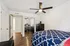 Bright bedroom with stylish geometric bedding, sleek mirrored closet, and modern ceiling fan on elegant wooden flooring.