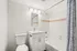 Bright and modern bathroom with elegant white vanity, sleek mirror, and inviting bathtub featuring a stylish blue patterned curtain.