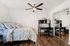 Chic bedroom with elegant design featuring a cozy bed, stylish desk, and mirrored closet doors, complemented by warm wooden flooring and a modern ceiling fan.