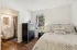 Cozy bedroom featuring stylish decor, inviting bed with 'Welcome Home' pillow, elegant dresser, adjacent modern bathroom, and a large window bringing in natural light.