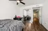 Inviting bedroom with modern ceiling fan, cozy double bed, mirrored wardrobe, and elegant desk, showcasing stylish hardwood flooring.